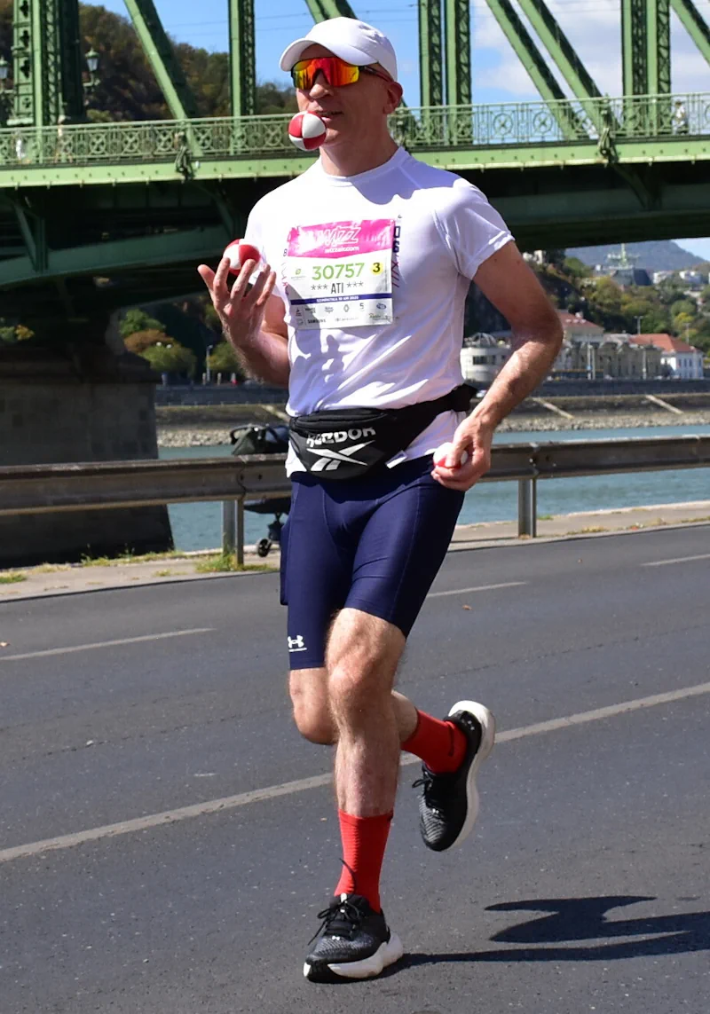Futás közbeni zsonglőrködés a Wizz Air 2026-os Szimpatika 10 km-es távján. Háttérben a Szabadság híd.